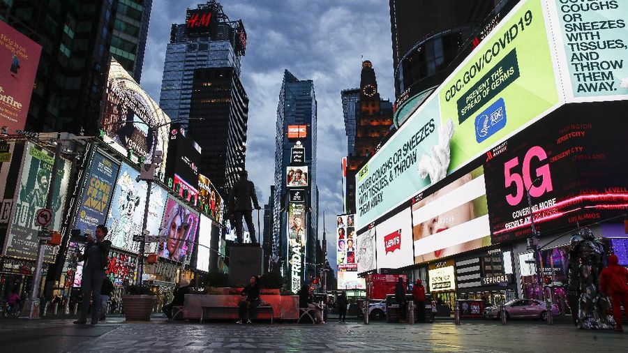FILE - This March 20, 2020 file photo, shows a screen displaying messages concerning COVID-19, right, in a sparsely populated Times Square in New York. COVID-19 has shaken theater fans and shuttered all New York City's venues, including Broadway, which grossed $1.8 billion last season and attracted a record 15 million people. How Broadway — one the city's jewels — will reopen is still not clear. (AP Photo/John Minchillo, File)