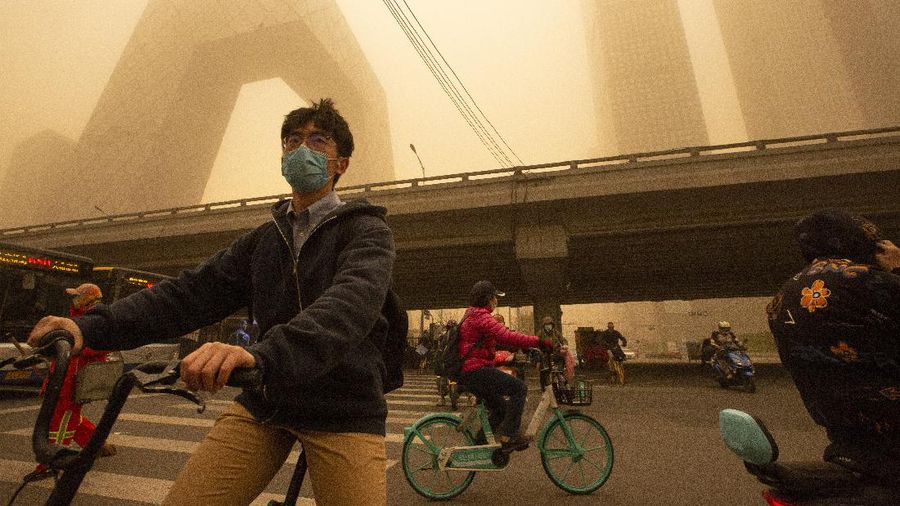 People wait to cross an intersection amid a sandstorm during the morning rush hour in Beijing, Monday, March 15, 2021. The sandstorm brought a tinted haze to Beijing's skies and sent air quality indices soaring on Monday. (AP Photo/Mark Schiefelbein)