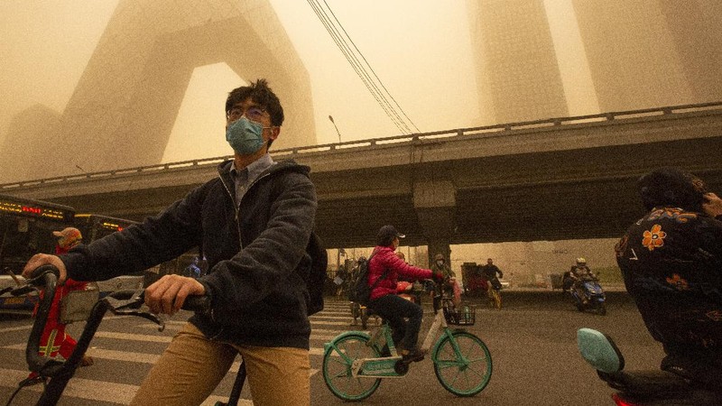 People wait to cross an intersection amid a sandstorm during the morning rush hour in Beijing, Monday, March 15, 2021. The sandstorm brought a tinted haze to Beijing's skies and sent air quality indices soaring on Monday. (AP Photo/Mark Schiefelbein)