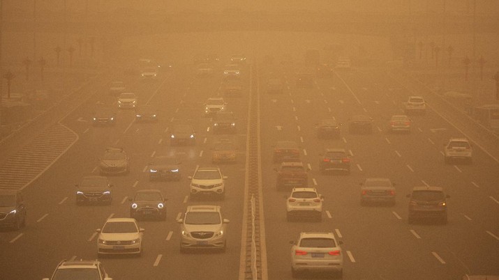 People wait to cross an intersection amid a sandstorm during the morning rush hour in Beijing, Monday, March 15, 2021. The sandstorm brought a tinted haze to Beijing's skies and sent air quality indices soaring on Monday. (AP Photo/Mark Schiefelbein)