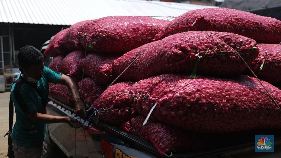 Pekerja menurunkan bawang merah yang baru tiba dari Brebes, Jawa Tengah di Pasar Kramat Jati, Jakarta, Rabu (17/3/2021).  Menurut pedagang setempat harga bawang merah di Jakarta naik dari harga 17 ribu menjadi 28 ribu per kilo gram karena meningkatnya permintaan dan sedikitnya stok bawang merah pada musim penghujan. Pantauan CNBC Indonesia permintaan bawang merah mulai sepi peminat, dari kios Los H bawang merah masih banyak stok. (CNBC Indonesia/ Tri Susilo)