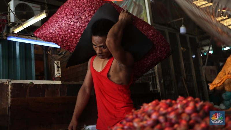 Pekerja menurunkan bawang merah yang baru tiba dari Brebes, Jawa Tengah di Pasar Kramat Jati, Jakarta, Rabu (17/3/2021).  Menurut pedagang setempat harga bawang merah di Jakarta naik dari harga 17 ribu menjadi 28 ribu per kilo gram karena meningkatnya permintaan dan sedikitnya stok bawang merah pada musim penghujan. Pantauan CNBC Indonesia permintaan bawang merah mulai sepi peminat, dari kios Los H bawang merah masih banyak stok. (CNBC Indonesia/ Tri Susilo)