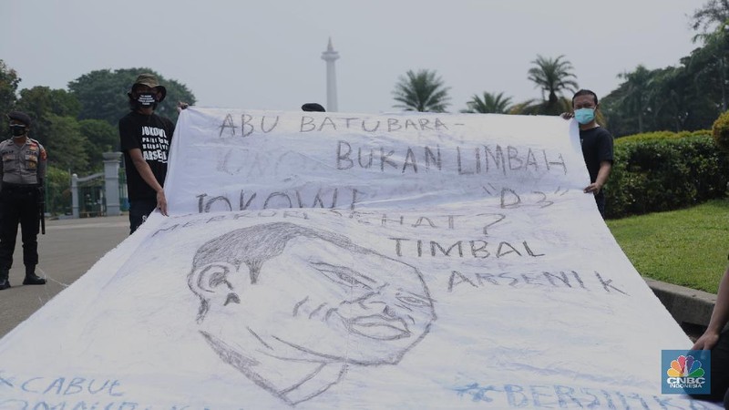 Sejumlah aktivis melakukan aksi simbolik menuntut Presiden Joko Widodo untuk mencabut Omnibus Law UU Cipta Kerja dan regulasi turunannya yang menghapus Fly Ash Bottom Ash (FABA) dari daftar limbah B3.di Kawasan Patung Kuda, Jakarta, 18 Maret 2021. (CNBC Indonesia/ Tri Susilo)