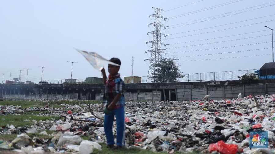 Warga melintas di kolong tol  Ir Wiyoto, Kelurahan Papanggo, Tanjung Priok, Jakarta, Kamis (18/3/2021). Tumpukan sampah plastik makanan dan limbah rumah tangga Tampak sudah melebur dengan tanah. Pantauan CNBC Indonesia di lokasi warga masih ada yang membuang sampah dilokasi walaupun sudah di tegur dengan warga sekitar. Yanto salah satu warga mengatakan 