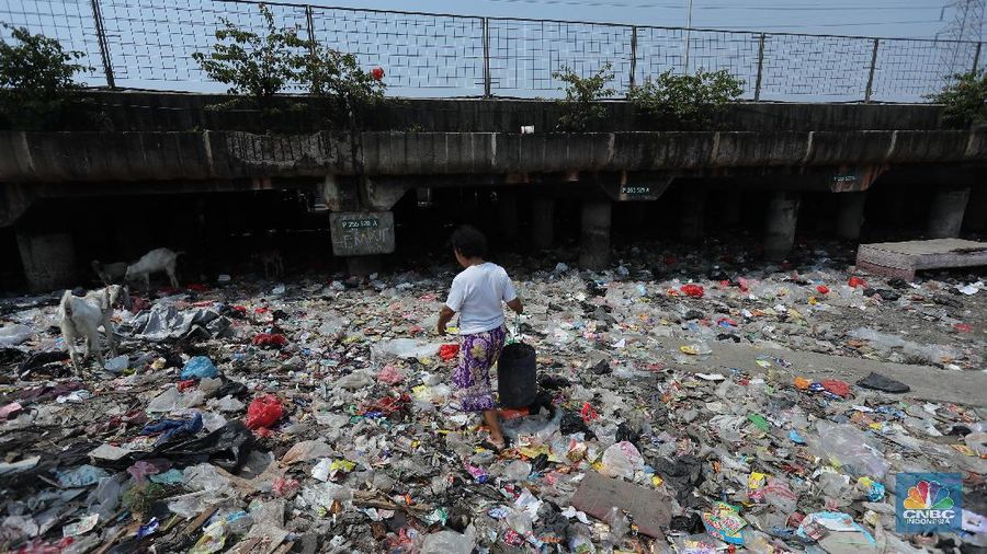 Warga melintas di kolong tol  Ir Wiyoto, Kelurahan Papanggo, Tanjung Priok, Jakarta, Kamis (18/3/2021). Tumpukan sampah plastik makanan dan limbah rumah tangga Tampak sudah melebur dengan tanah. Pantauan CNBC Indonesia di lokasi warga masih ada yang membuang sampah dilokasi walaupun sudah di tegur dengan warga sekitar. Yanto salah satu warga mengatakan 