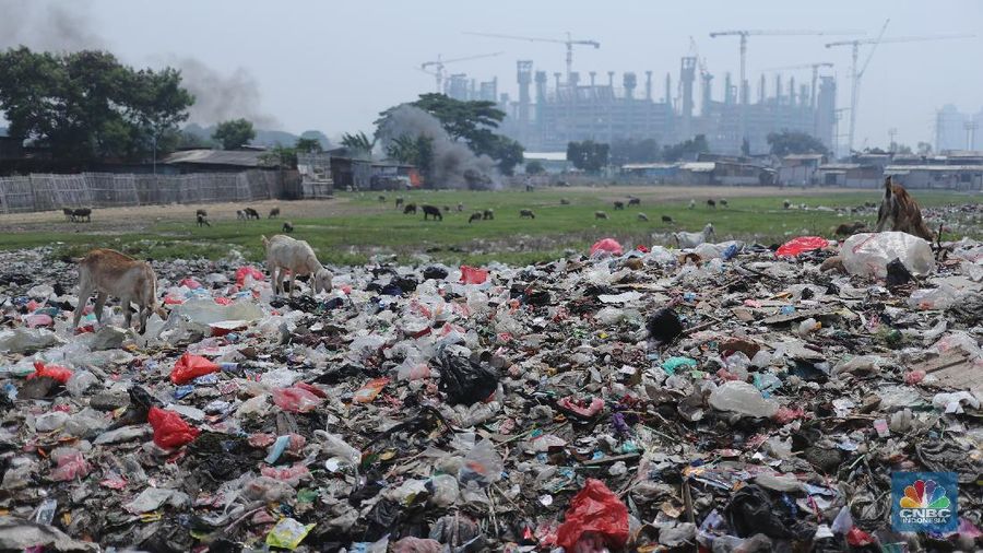 Warga melintas di kolong tol Ir Wiyoto, Kelurahan Papanggo, Tanjung Priok, Jakarta, Kamis (18/3/2021). Tumpukan sampah plastik makanan dan limbah rumah tangga Tampak sudah melebur dengan tanah. Pantauan CNBC Indonesia di lokasi warga masih ada yang membuang sampah dilokasi walaupun sudah di tegur dengan warga sekitar. Yanto salah satu warga mengatakan