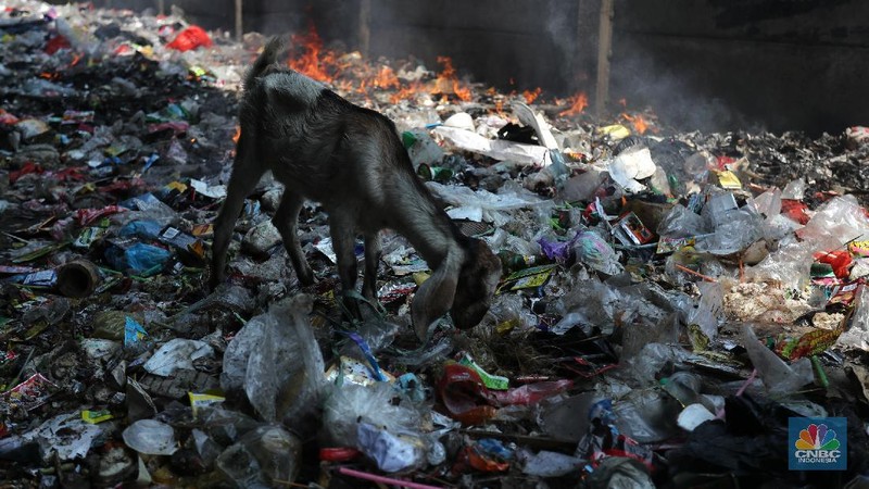Warga melintas di kolong tol  Ir Wiyoto, Kelurahan Papanggo, Tanjung Priok, Jakarta, Kamis (18/3/2021). Tumpukan sampah plastik makanan dan limbah rumah tangga Tampak sudah melebur dengan tanah. Pantauan CNBC Indonesia di lokasi warga masih ada yang membuang sampah dilokasi walaupun sudah di tegur dengan warga sekitar. Yanto salah satu warga mengatakan 