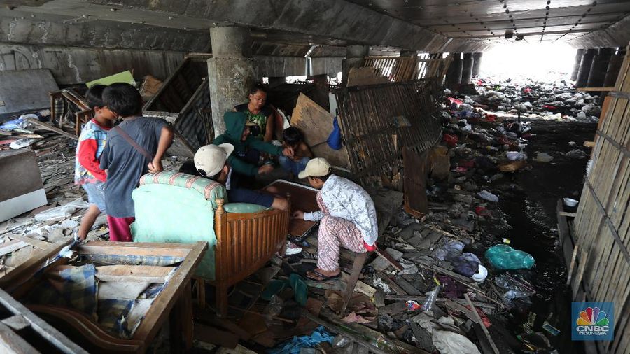 Warga melintas di kolong tol  Ir Wiyoto, Kelurahan Papanggo, Tanjung Priok, Jakarta, Kamis (18/3/2021). Tumpukan sampah plastik makanan dan limbah rumah tangga Tampak sudah melebur dengan tanah. Pantauan CNBC Indonesia di lokasi warga masih ada yang membuang sampah dilokasi walaupun sudah di tegur dengan warga sekitar. Yanto salah satu warga mengatakan 
