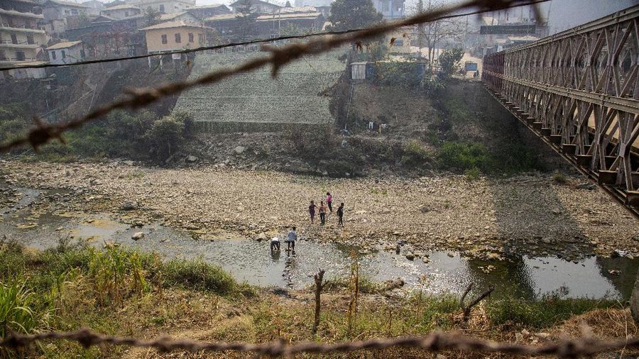 Unidentified people cross Tiau river which bifurcates India and Myanmar border, in Champhai village in Mizoram, India, Saturday, March 20, 2021.  Several Myanmar police officers who fled to India after defying army orders to shoot opponents of last month’s coup are urging Prime Minister Narendra Modi’s government to not repatriate them and provide them political asylum on humanitarian grounds. (AP Photo/Anupam Nath)