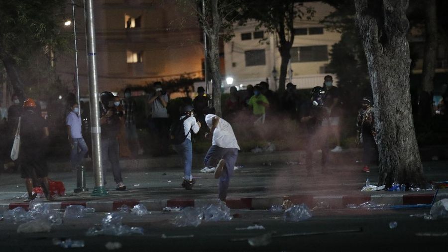 A riot policeman advances towards a man kneeling on the road after the dispersal of protesters who removed container vans used as a barricade in front of the Grand Palace Saturday, March 20, 2021 in Bangkok, Thailand. Thailand's student-led pro-democracy movement is holding a rally in the Thai capital, seeking to press demands that include freedom for their leaders, who are being held without bail on charges of defaming the monarchy. (AP Photo/Sakchai Lalit)