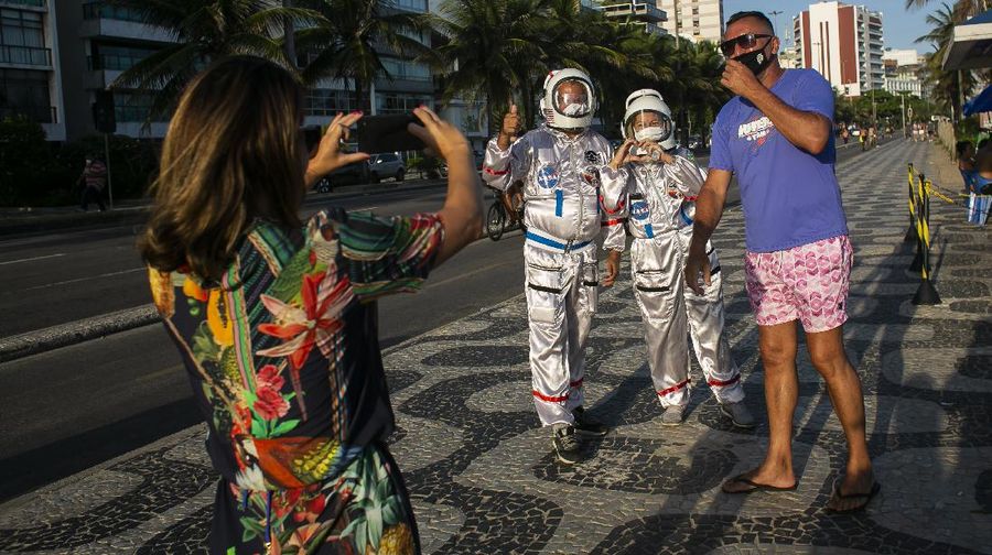 Accountant Tercio Galdino and wife Alicea, dressed in their astronaut costumes, watch as bystanders make photos of them on Ipanema beach in Rio de Janeiro, Brazil, Saturday, March 20, 2021. The Galdinos have come up with a unique way for protecting themselves and drawing awareness around COVID-19 protective measures – by dressing as astronauts. The pair first began to traverse the iconic beaches fully suited in mid 2020 at the height of the first wave of the pandemic in Brazil, now as cases surge once again they are taking their ‘astronaut walks’ back to the promenades. (AP Photo/Bruna Prado)