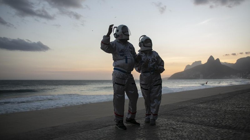 Accountant Tercio Galdino and wife Alicea, dressed in their astronaut costumes, watch as bystanders make photos of them on Ipanema beach in Rio de Janeiro, Brazil, Saturday, March 20, 2021. The Galdinos have come up with a unique way for protecting themselves and drawing awareness around COVID-19 protective measures – by dressing as astronauts. The pair first began to traverse the iconic beaches fully suited in mid 2020 at the height of the first wave of the pandemic in Brazil, now as cases surge once again they are taking their ‘astronaut walks’ back to the promenades. (AP Photo/Bruna Prado)