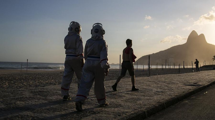 Accountant Tercio Galdino and wife Alicea, dressed in their astronaut costumes, watch as bystanders make photos of them on Ipanema beach in Rio de Janeiro, Brazil, Saturday, March 20, 2021. The Galdinos have come up with a unique way for protecting themselves and drawing awareness around COVID-19 protective measures – by dressing as astronauts. The pair first began to traverse the iconic beaches fully suited in mid 2020 at the height of the first wave of the pandemic in Brazil, now as cases surge once again they are taking their ‘astronaut walks’ back to the promenades. (AP Photo/Bruna Prado)