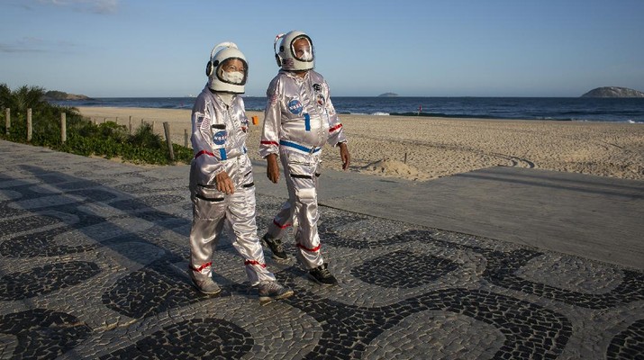 Accountant Tercio Galdino and wife Alicea, dressed in their astronaut costumes, watch as bystanders make photos of them on Ipanema beach in Rio de Janeiro, Brazil, Saturday, March 20, 2021. The Galdinos have come up with a unique way for protecting themselves and drawing awareness around COVID-19 protective measures – by dressing as astronauts. The pair first began to traverse the iconic beaches fully suited in mid 2020 at the height of the first wave of the pandemic in Brazil, now as cases surge once again they are taking their ‘astronaut walks’ back to the promenades. (AP Photo/Bruna Prado)