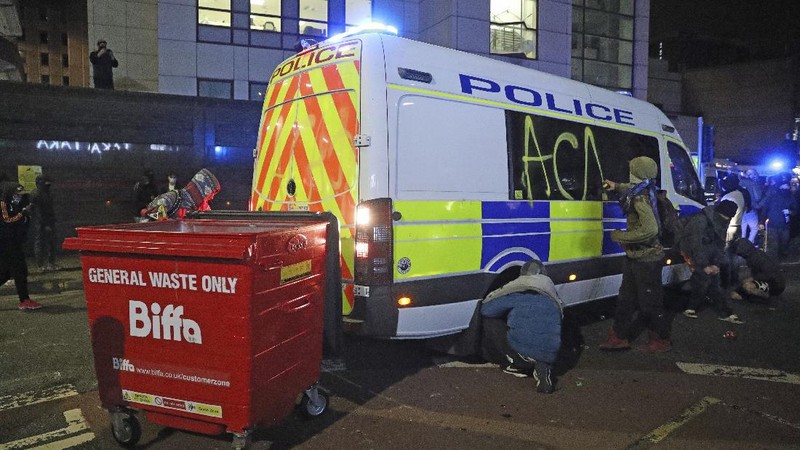 Protesters set fire to a vandalized police van outside Bridewell Police Station, in Bristol, England, Sunday March 21, 2021, as people took part in a protest demonstrating against the Police and Crime Bill. (Andrew Matthews/PA via AP)
