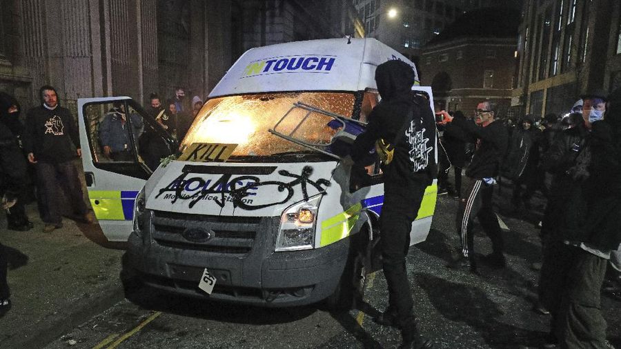 Protesters set fire to a vandalized police van outside Bridewell Police Station, in Bristol, England, Sunday March 21, 2021, as people took part in a protest demonstrating against the Police and Crime Bill. (Andrew Matthews/PA via AP)