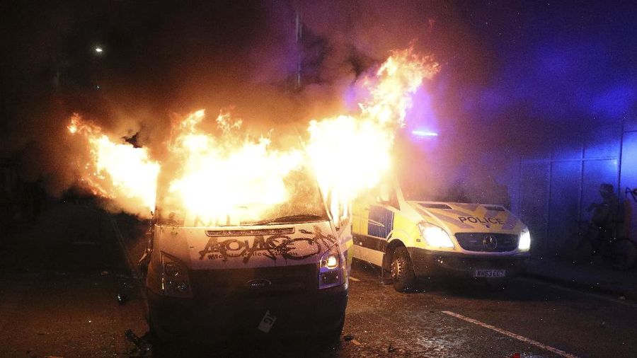 Protesters set fire to a vandalized police van outside Bridewell Police Station, in Bristol, England, Sunday March 21, 2021, as people took part in a protest demonstrating against the Police and Crime Bill. (Andrew Matthews/PA via AP)