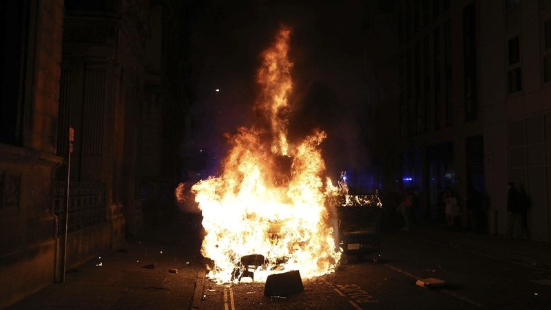 Protesters set fire to a vandalized police van outside Bridewell Police Station, in Bristol, England, Sunday March 21, 2021, as people took part in a protest demonstrating against the Police and Crime Bill. (Andrew Matthews/PA via AP)