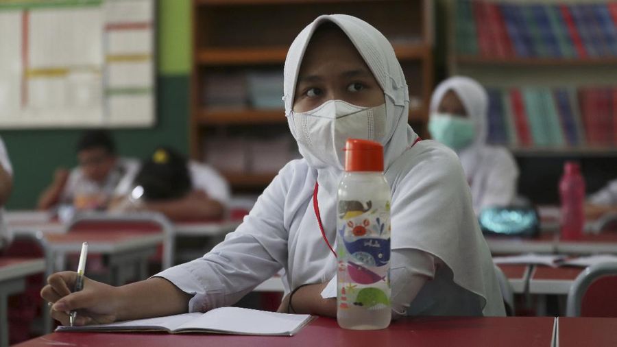 A teacher wears a face mask as a precaution against the coronavirus during a class in Bekasi on the outskirts of Jakarta, Indonesia. Tuesday, March 23, 2021. (AP Photo/Achmad Ibrahim)