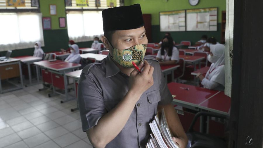 A teacher wears a face mask as a precaution against the coronavirus during a class in Bekasi on the outskirts of Jakarta, Indonesia. Tuesday, March 23, 2021. (AP Photo/Achmad Ibrahim)