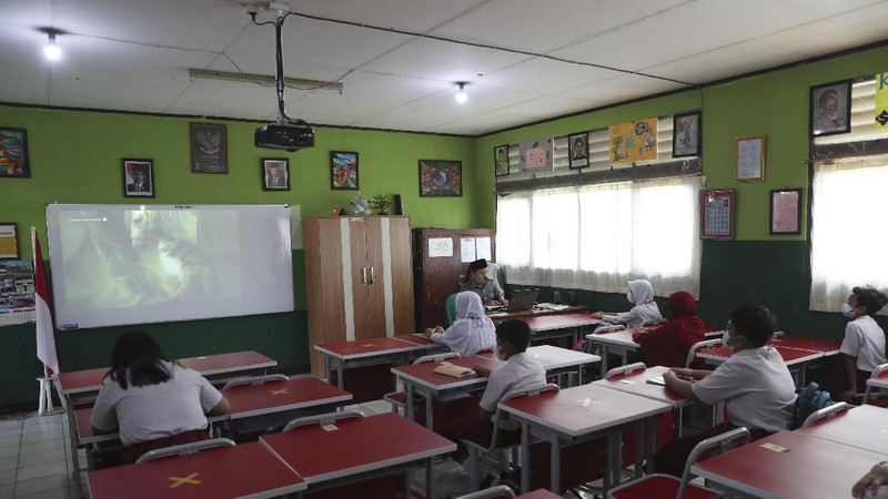 A teacher wears a face mask as a precaution against the coronavirus during a class in Bekasi on the outskirts of Jakarta, Indonesia. Tuesday, March 23, 2021. (AP Photo/Achmad Ibrahim)