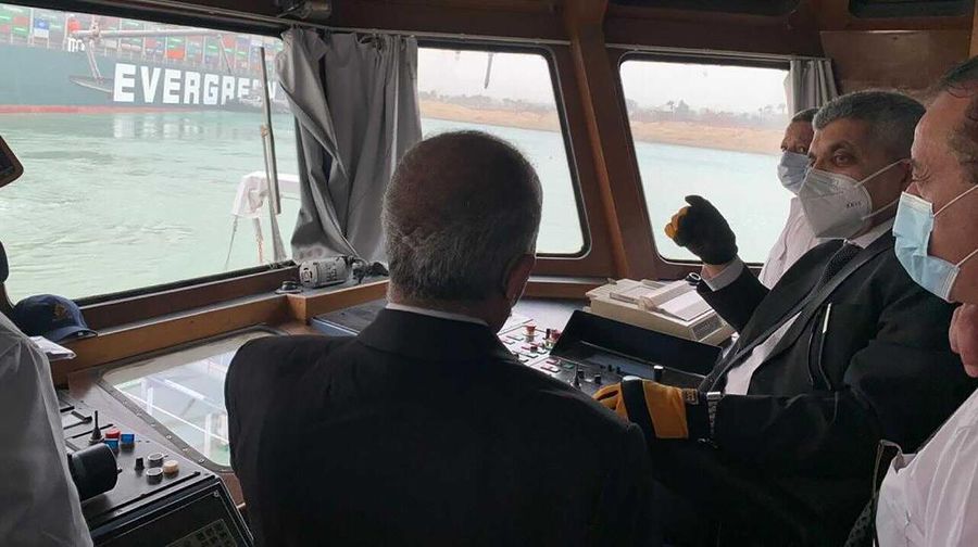 In this photo released by the Suez Canal Authority, a boat navigates in front of a massive cargo ship, named the Ever Green, rear, sits grounded Wednesday, March 24, 2021, after it turned sideways in Egypt’s Suez Canal, blocking traffic in a crucial East-West waterway for global shipping. An Egyptian official warned Wednesday it could take at least two days to clear the ship. (Suez Canal Authority via AP)
