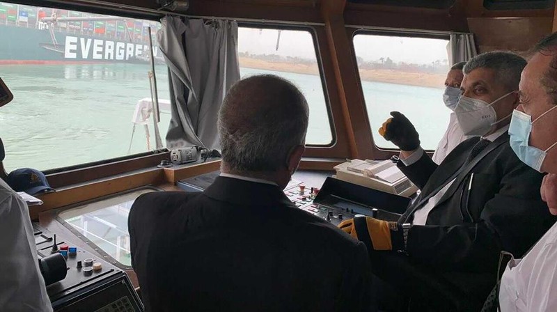 In this photo released by the Suez Canal Authority, a boat navigates in front of a massive cargo ship, named the Ever Green, rear, sits grounded Wednesday, March 24, 2021, after it turned sideways in Egypt’s Suez Canal, blocking traffic in a crucial East-West waterway for global shipping. An Egyptian official warned Wednesday it could take at least two days to clear the ship. (Suez Canal Authority via AP)