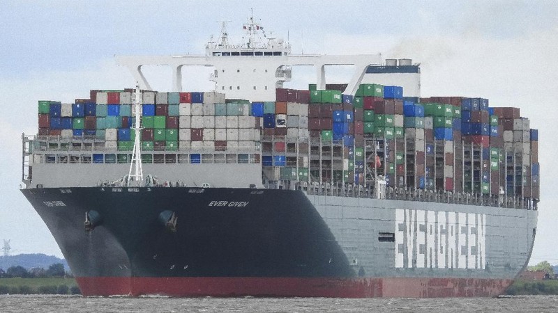 In this photo released by the Suez Canal Authority, a boat navigates in front of a massive cargo ship, named the Ever Green, rear, sits grounded Wednesday, March 24, 2021, after it turned sideways in Egypt’s Suez Canal, blocking traffic in a crucial East-West waterway for global shipping. An Egyptian official warned Wednesday it could take at least two days to clear the ship. (Suez Canal Authority via AP)