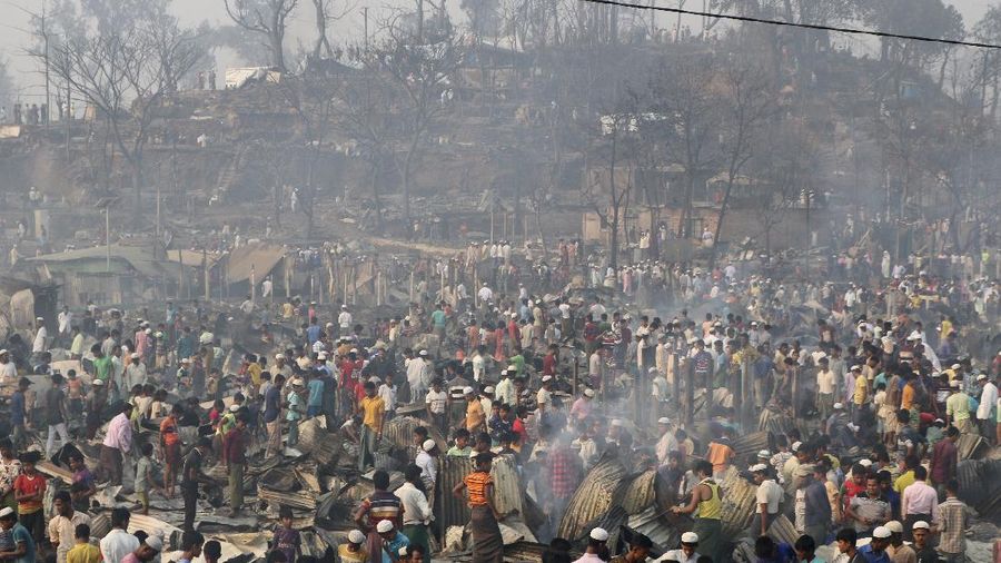 Rohingya refugees stand at the site of Monday's fire at a refugee camp in Balukhali, southern Bangladesh, Tuesday, March 23, 2021. Rescuers recovered more than a dozen charred bodies from a Rohingya refugee camp in southern Bangladesh after a devastating fire that destroyed thousands of shelters, officials said Tuesday. (AP Photo/ Shafiqur Rahman)