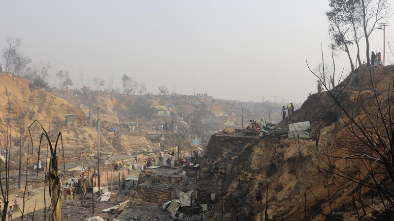 Rohingya refugees stand at the site of Monday's fire at a refugee camp in Balukhali, southern Bangladesh, Tuesday, March 23, 2021. Rescuers recovered more than a dozen charred bodies from a Rohingya refugee camp in southern Bangladesh after a devastating fire that destroyed thousands of shelters, officials said Tuesday. (AP Photo/ Shafiqur Rahman)