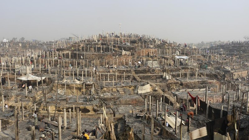 Rohingya refugees stand at the site of Monday's fire at a refugee camp in Balukhali, southern Bangladesh, Tuesday, March 23, 2021. Rescuers recovered more than a dozen charred bodies from a Rohingya refugee camp in southern Bangladesh after a devastating fire that destroyed thousands of shelters, officials said Tuesday. (AP Photo/ Shafiqur Rahman)