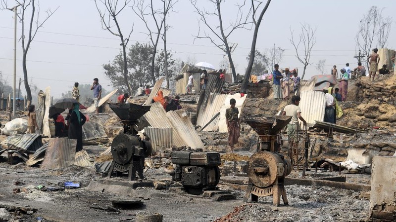 Rohingya refugees stand at the site of Monday's fire at a refugee camp in Balukhali, southern Bangladesh, Tuesday, March 23, 2021. Rescuers recovered more than a dozen charred bodies from a Rohingya refugee camp in southern Bangladesh after a devastating fire that destroyed thousands of shelters, officials said Tuesday. (AP Photo/ Shafiqur Rahman)