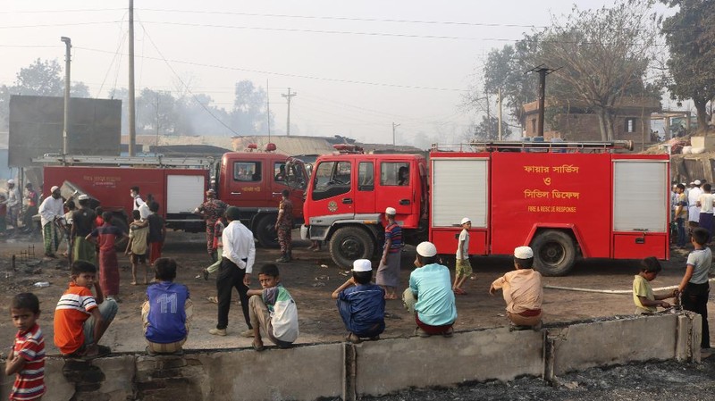 Rohingya refugees stand at the site of Monday's fire at a refugee camp in Balukhali, southern Bangladesh, Tuesday, March 23, 2021. Rescuers recovered more than a dozen charred bodies from a Rohingya refugee camp in southern Bangladesh after a devastating fire that destroyed thousands of shelters, officials said Tuesday. (AP Photo/ Shafiqur Rahman)
