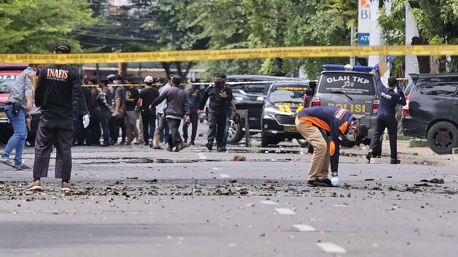 Police officers inspect the area near a church where an explosion went off in Makassar, South Sulawesi, Indonesia, Sunday, March 28, 2021. A suicide bomber blew himself up outside a packed Roman Catholic cathedral on Indonesia's Sulawesi island during a Palm Sunday Mass, wounding a number of people, police said. (AP Photo/Masyudi S. Firmansyah)