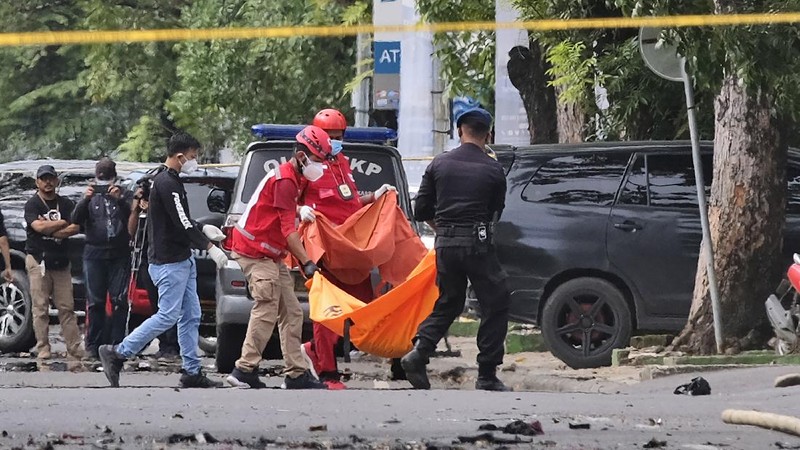 Police officer and rescue workers carry a body bag containing what is believed to be human remains outside a church where an explosion went off in Makassar, South Sulawesi, Indonesia, Sunday, March 28, 2021. A suicide bomber blew himself up outside a packed Roman Catholic cathedral on Indonesia's Sulawesi island during a Palm Sunday Mass, wounding a number of people, police said. (AP Photo/Masyudi S. Firmansyah)