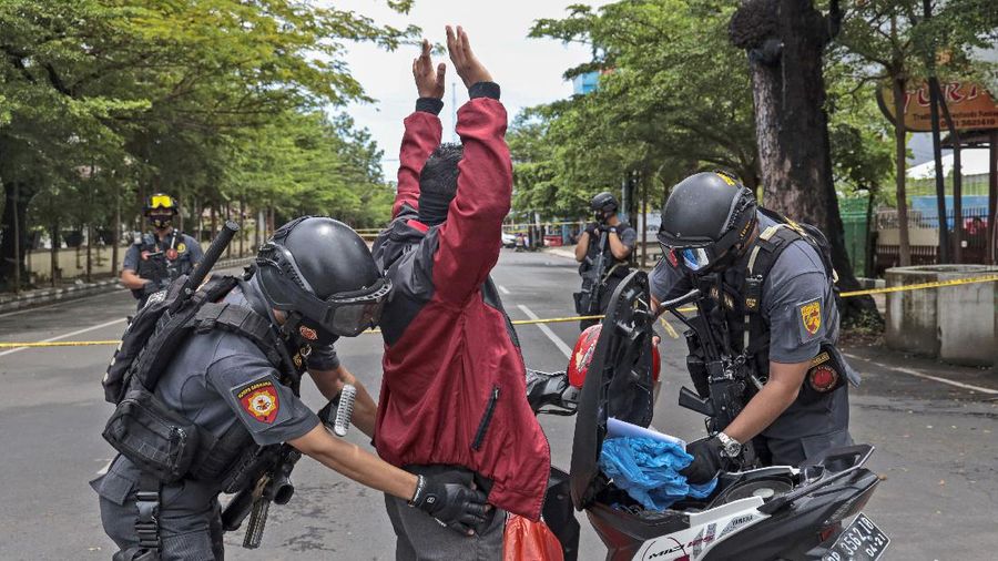 Police officers stand guard during a raid on a house that, police believe, is linked to the suicide bombers of Sunday's church attack, in Makassar, South Sulawesi, Indonesia, Monday, March 29, 2021. Two attackers believed to be members of a militant network that pledged allegiance to the Islamic State group blew themselves up outside the packed Roman Catholic cathedral during a Palm Sunday Mass on Indonesia's Sulawesi island, wounding a number of people, police said. (AP Photo/Daeng Mansur)
