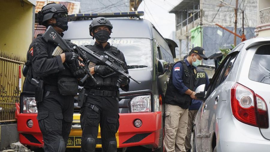 Police officers stand guard during a raid on a house that, police believe, is linked to the suicide bombers of Sunday's church attack, in Makassar, South Sulawesi, Indonesia, Monday, March 29, 2021. Two attackers believed to be members of a militant network that pledged allegiance to the Islamic State group blew themselves up outside the packed Roman Catholic cathedral during a Palm Sunday Mass on Indonesia's Sulawesi island, wounding a number of people, police said. (AP Photo/Daeng Mansur)