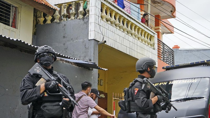 Police officers stand guard during a raid on a house that, police believe, is linked to the suicide bombers of Sunday's church attack, in Makassar, South Sulawesi, Indonesia, Monday, March 29, 2021. Two attackers believed to be members of a militant network that pledged allegiance to the Islamic State group blew themselves up outside the packed Roman Catholic cathedral during a Palm Sunday Mass on Indonesia's Sulawesi island, wounding a number of people, police said. (AP Photo/Daeng Mansur)