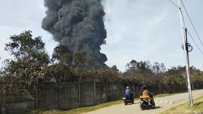Motorists ride past as thick smoke billows from a fire that razes through Pertamina Balongan Refinery in Indramayu, West Java, Indonesia, Monday, March 29, 2021. Hundreds of people living in villages around the refinery have been evacuated following the fire that broke out after midnight on Monday. (AP Photo)