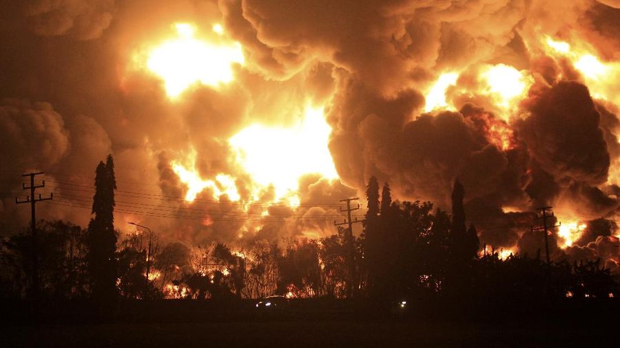 A car passes by as smoke billows from a fire that razes through Pertamina Balongan Refinery in Indramayu, West Java, Indonesia, Monday, March 29, 2021. Hundreds of people were evacuated from a nearby village after the massive fire broke out at the refinery. (AP Photo)