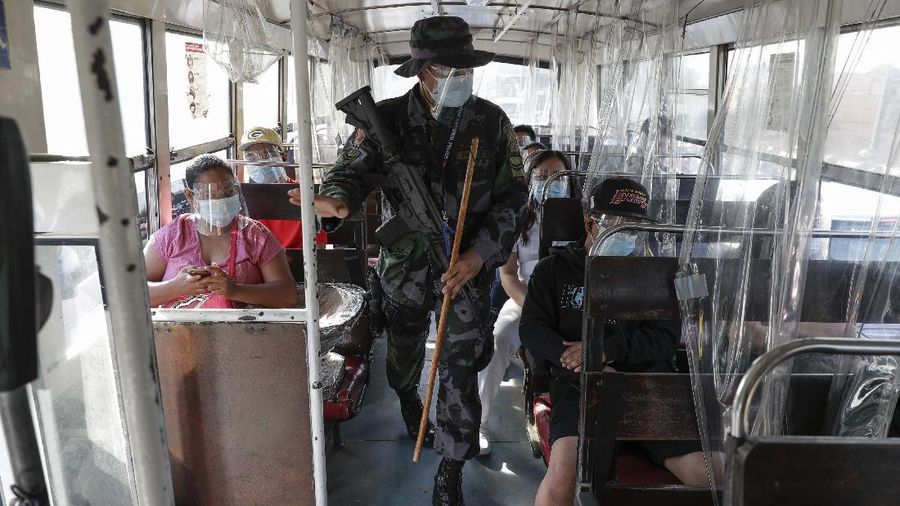 A woman wearing a face mask walks at a village on the second day of a stricter lockdown to prevent the spread of the coronavirus in the outskirts of Quezon City, Philippines on Tuesday, March 30, 2021. Philippine officials placed Metropolitan Manila and four outlying provinces, a region of more than 25 million people, back to a lockdown Monday at the height of the Lenten and Easter holiday travel season as they scrambled to control an alarming surge in coronavirus infections. (AP Photo/Aaron Favila)