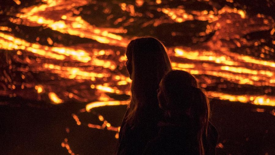 People watch as lava flows from an eruption of a volcano on the Reykjanes Peninsula in southwestern Iceland late on Monday, March 29, 2021. Iceland's latest volcano eruption is still attracting crowds of people hoping to get close to the gentle lava flows. The eruption in Geldingadalur, near Iceland's capital Reykjavik, is not seen as a threat to nearby towns and the slow flows mean people can get close to action without too much harm. (AP Photo/Marco Di Marco)
