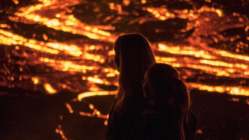 People watch as lava flows from an eruption of a volcano on the Reykjanes Peninsula in southwestern Iceland late on Monday, March 29, 2021. Iceland's latest volcano eruption is still attracting crowds of people hoping to get close to the gentle lava flows. The eruption in Geldingadalur, near Iceland's capital Reykjavik, is not seen as a threat to nearby towns and the slow flows mean people can get close to action without too much harm. (AP Photo/Marco Di Marco)