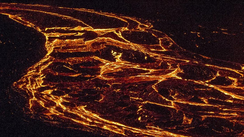 People watch as lava flows from an eruption of a volcano on the Reykjanes Peninsula in southwestern Iceland late on Monday, March 29, 2021. Iceland's latest volcano eruption is still attracting crowds of people hoping to get close to the gentle lava flows. The eruption in Geldingadalur, near Iceland's capital Reykjavik, is not seen as a threat to nearby towns and the slow flows mean people can get close to action without too much harm. (AP Photo/Marco Di Marco)