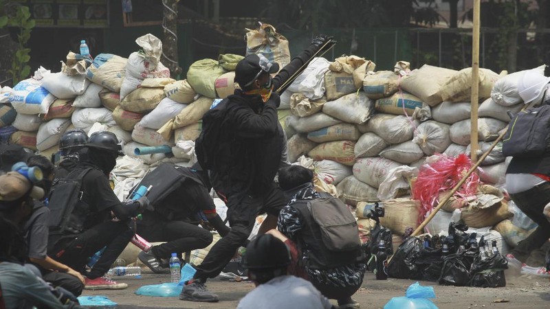 Anti-coup protesters use garbage to block a road as a form of 