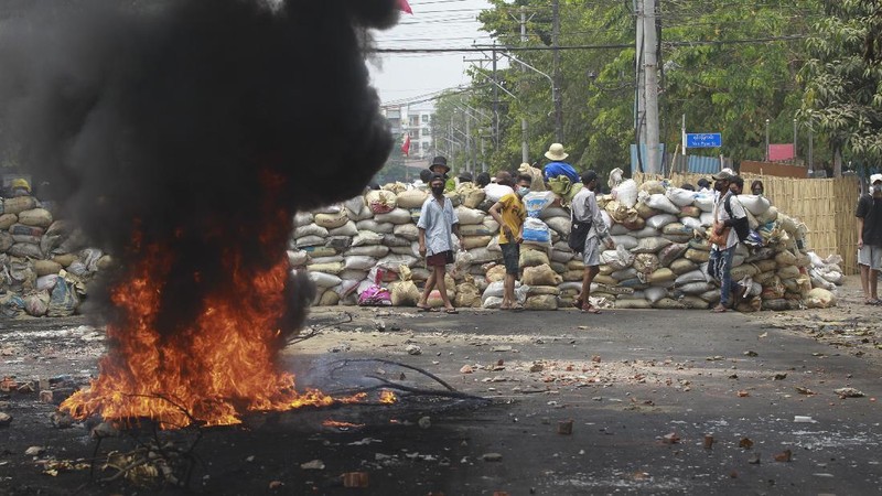 Anti-coup protesters use garbage to block a road as a form of 