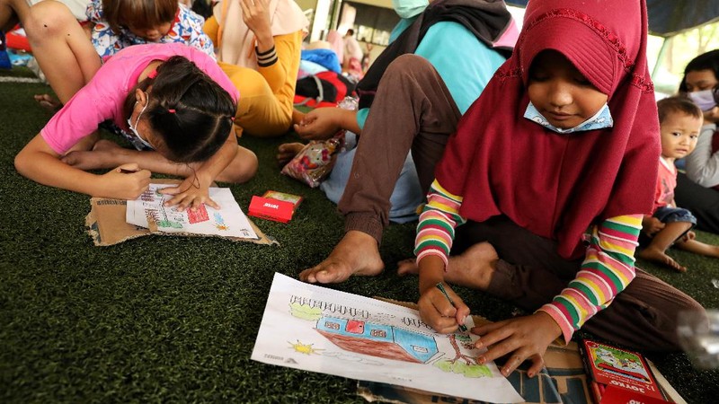 Sejumlah anak pengungsi dari kebakaran kilang Pertamina Balongan Indramayu mewarnai saat berada di tempat pengungsian di Lapangan Futsal GOR Bumi Patra, Indramayu, Jawa Barat, Rabu (31/3/2021). Kegiatan  mewarnai tersebut menjadi salah satu upaya penyembuhan trauma (trauma healing) yang diberikan oleh para relawan agar sejumlah anak-anak tetap ceria saat berada di lokasi pengungsian. (CNBC Indonesia/Andrean Kristianto)