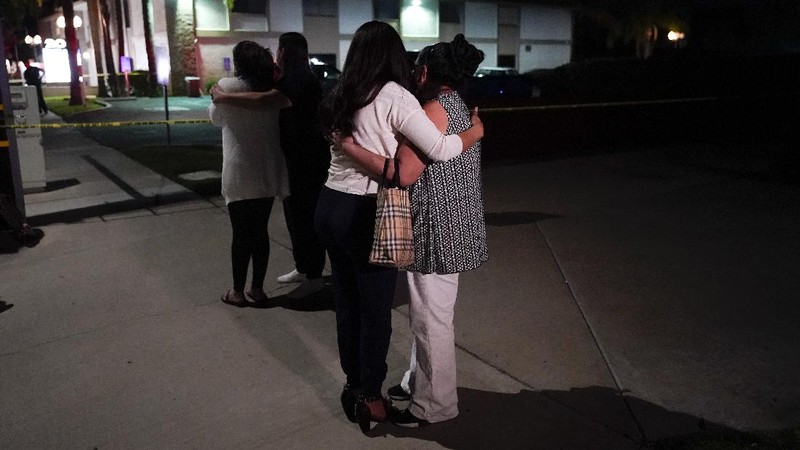 Unidentified people comfort each other as they stand near a business building where a shooting occurred in Orange, Calif., Wednesday, March 31, 2021. Police say several people were killed, including a child, and the suspected shooter was wounded by police. (AP Photo/Jae C. Hong)