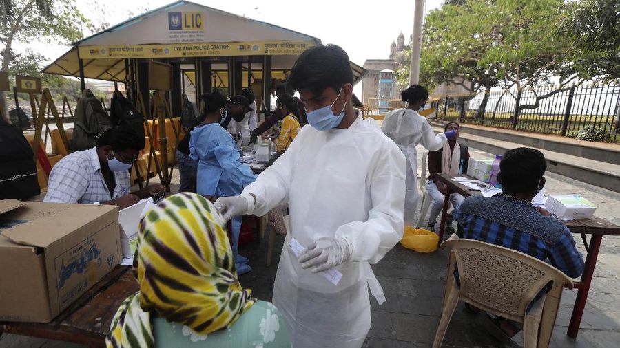 People wearing masks queue up to board buses in Mumbai, India, Monday, April 5, 2021. India reported its biggest single-day spike in confirmed coronavirus cases since the pandemic began Monday, and officials in the hard-hit state home to Mumbai are returning to the closure of some businesses and places of worship in a bid to slow the spread. (AP Photo/Rafiq Maqbool)