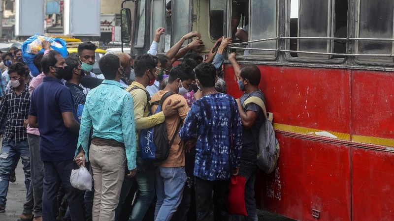 People wearing masks queue up to board buses in Mumbai, India, Monday, April 5, 2021. India reported its biggest single-day spike in confirmed coronavirus cases since the pandemic began Monday, and officials in the hard-hit state home to Mumbai are returning to the closure of some businesses and places of worship in a bid to slow the spread. (AP Photo/Rafiq Maqbool)